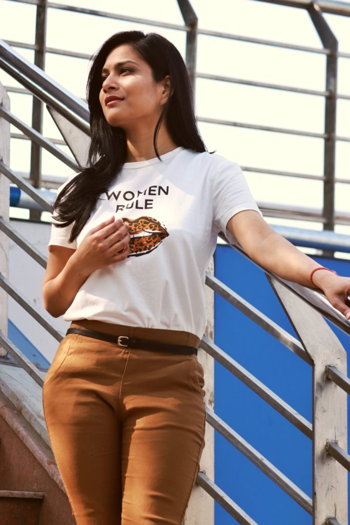 Girl wearing shein leapard print lips on white t shirt with brown skinny trousers and beige sports shoes