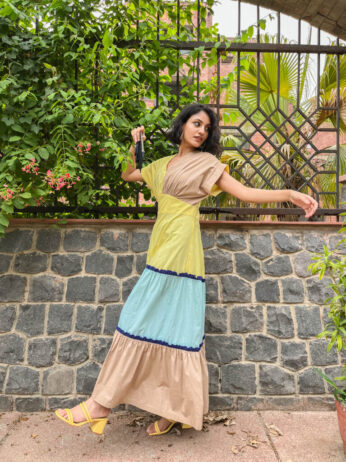 Women in Kanelle yellow dress standing near tree