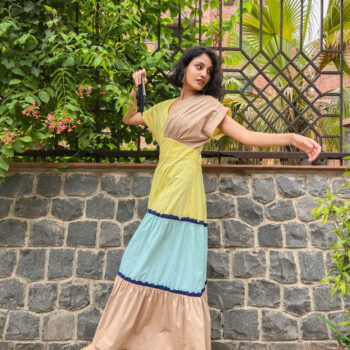 Women in Kanelle yellow dress standing near tree