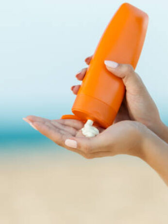 Woman hand apply sunscreen on the beach