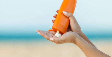 Woman hand apply sunscreen on the beach