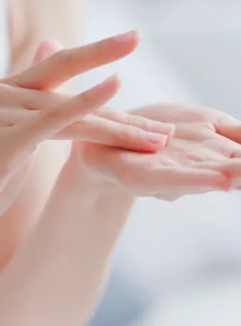 Close-up of hands applying moisturizer, demonstrating proper skincare technique.